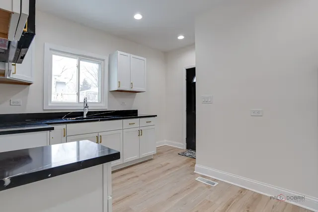 a kitchen with granite countertop white cabinets and wooden floor