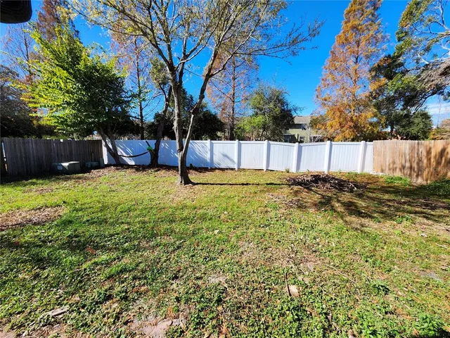 a view of a backyard with wooden fence and a large tree
