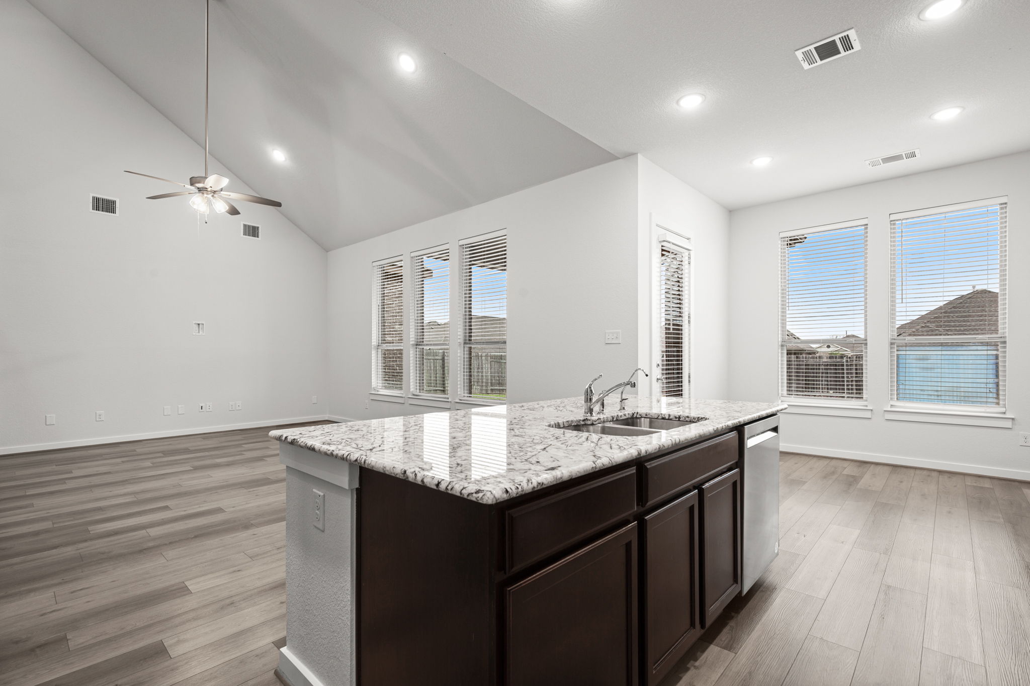 841 Spinnaker Loop Kyle, TX 78640 - Photo 19 of 40 Kitchen featuring high vaulted ceiling, dark brown cabinets, light wood-type flooring, recessed lighting, and light stone countertops