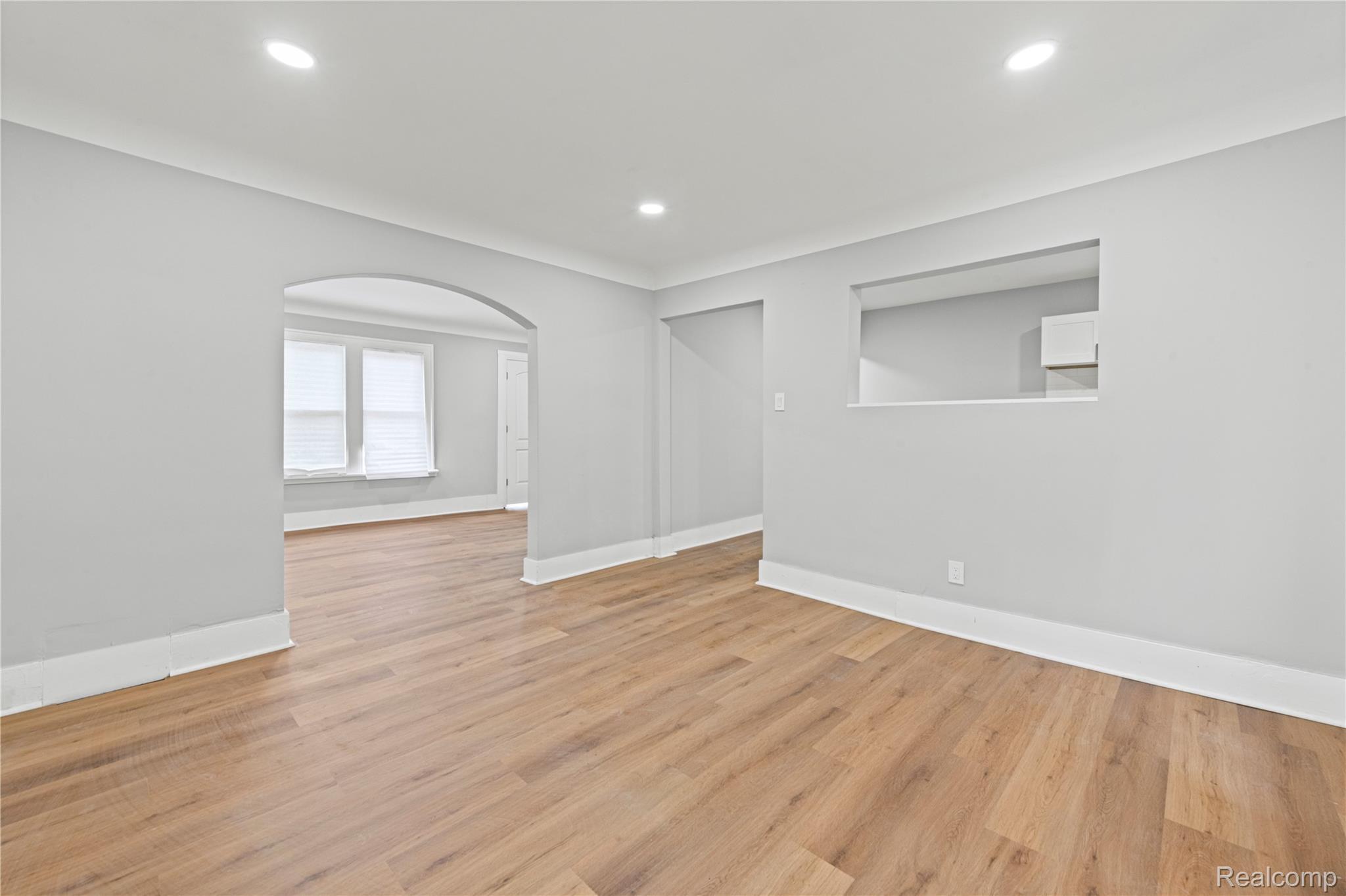 9175 Devonshire Road Detroit, MI 48224 - Photo 6 of 26 Recessed ceiling lighting, wood-finish flooring, arched doorway, pass-through window, and light gray wall paint