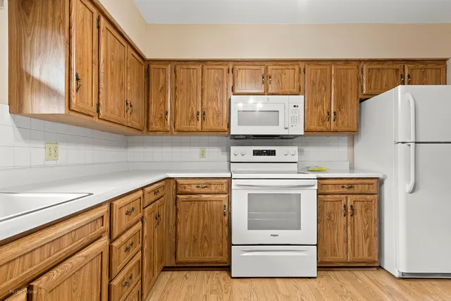 a kitchen with granite countertop a stove top oven a sink and dishwasher with white cabinets