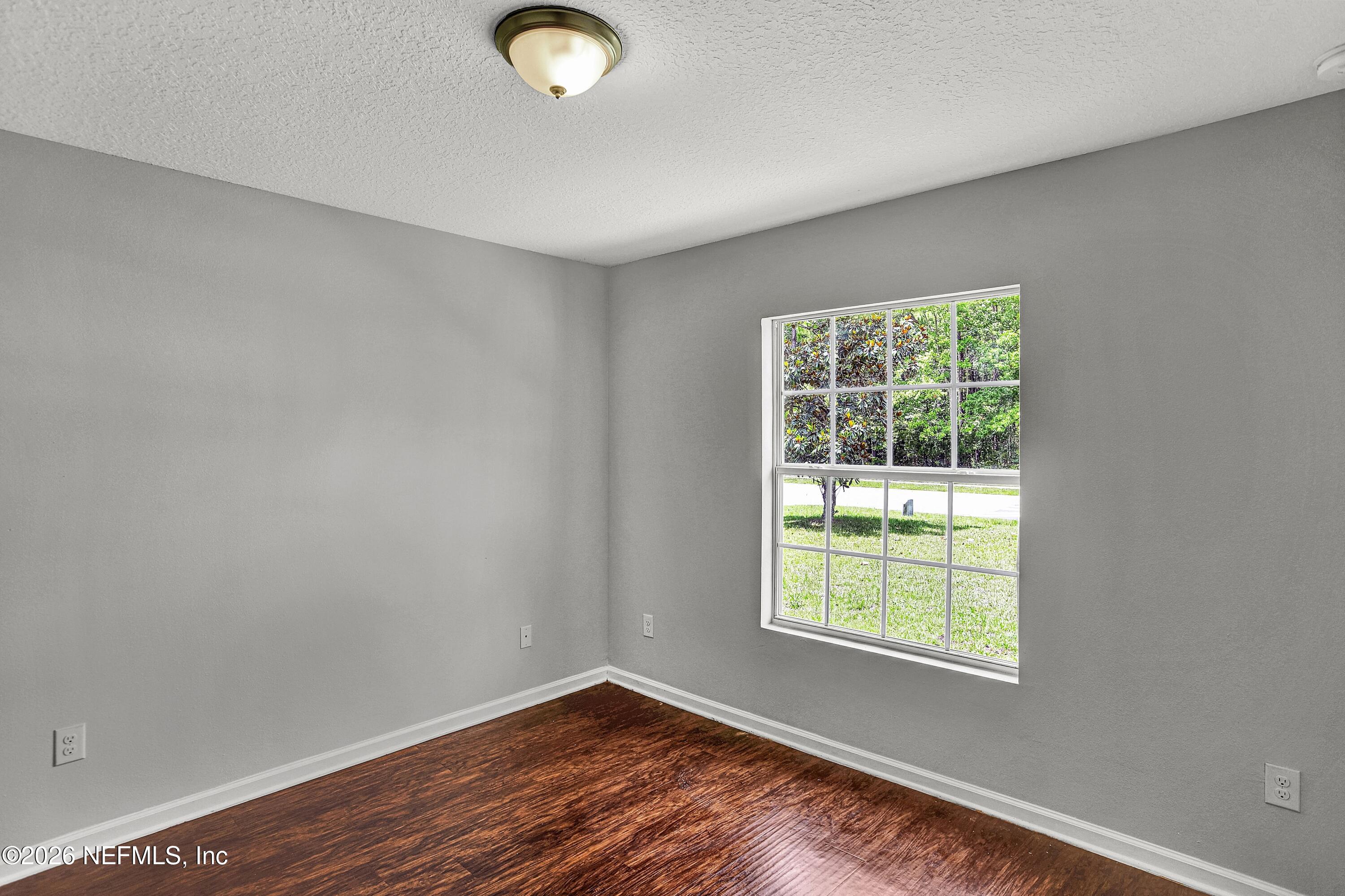 12271 Harts Road Jacksonville, FL 32218 - Photo 9 of 17 an empty room with wooden floor and windows