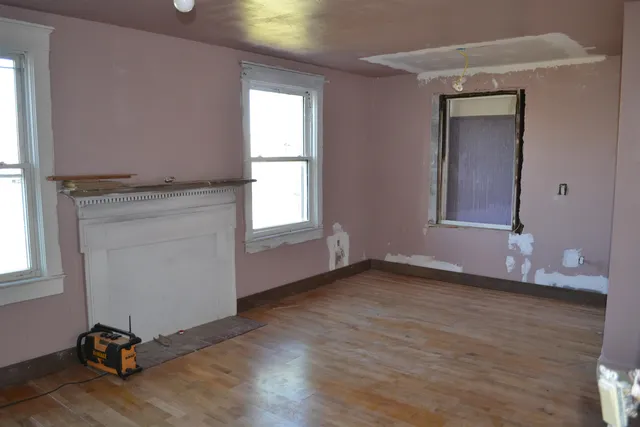 an empty room with wooden floor a ceiling fan and windows