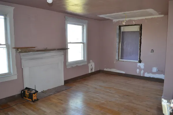 an empty room with wooden floor a ceiling fan and windows