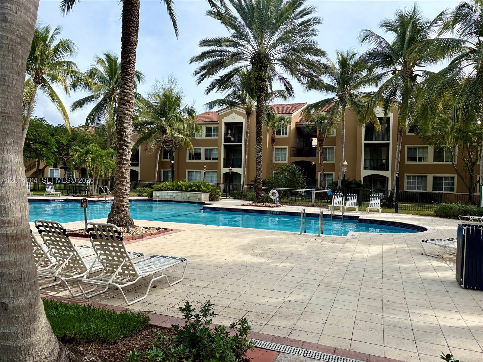 8030 North Nob Hill Road, Unit 105 Tamarac, FL 33321 - Photo 18 of 22 a view of a swimming pool with a table and chairs