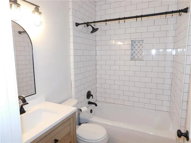 a bathroom with a granite countertop bathtub shower sink vanity and toilet