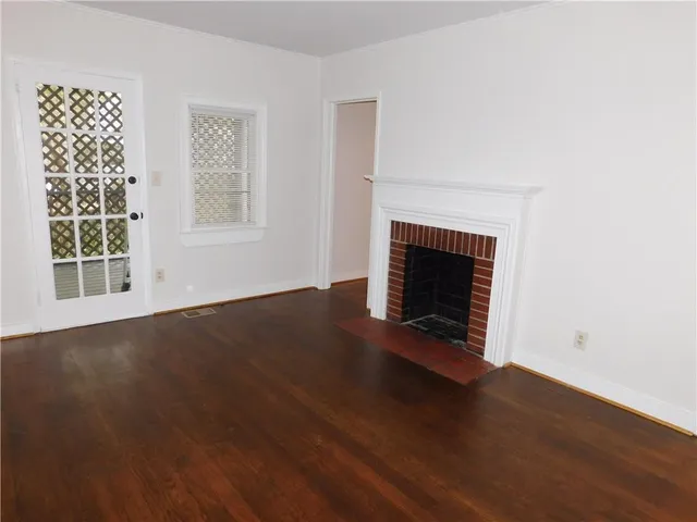 an empty room with wooden floor fireplace and windows