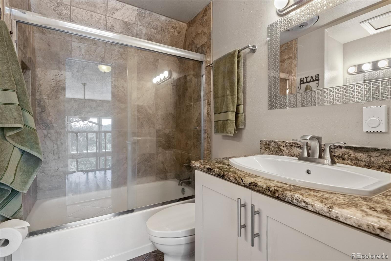 6637 High Drive Morrison, CO 80465 - Photo 17 of 28 a bathroom with a granite countertop sink a mirror a bathtub and shower