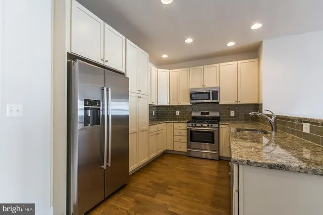 a kitchen with stainless steel appliances granite countertop a refrigerator a stove and a sink