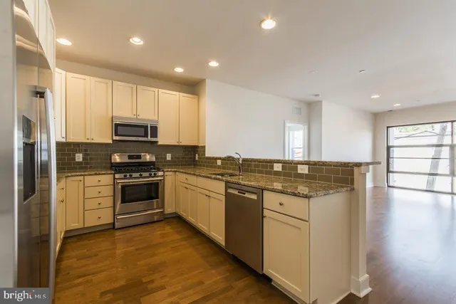 a kitchen with stainless steel appliances kitchen island granite countertop a stove a sink and a refrigerator