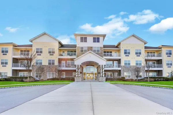 a front view of a building with a yard and trees