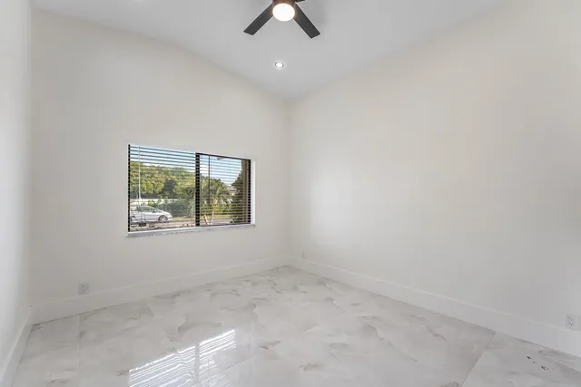 an empty room with ceiling fan and window
