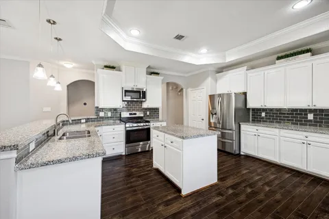 a kitchen with a refrigerator a stove top oven a sink and cabinets