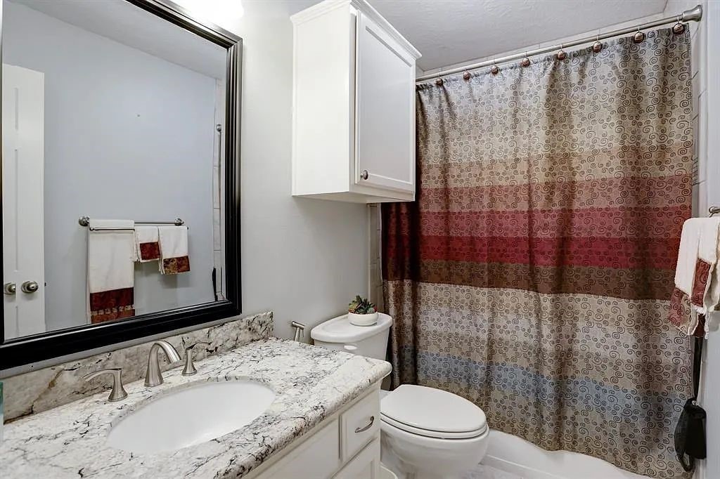 10147 Lazy Lagoon Houston, TX 77065 - Photo 13 of 15 a bathroom with a granite countertop sink toilet and shower