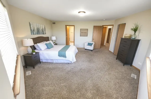 a spacious bedroom with a bed and wooden floor