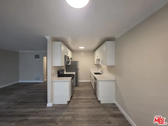 a kitchen with a sink wooden floor and stainless steel appliances