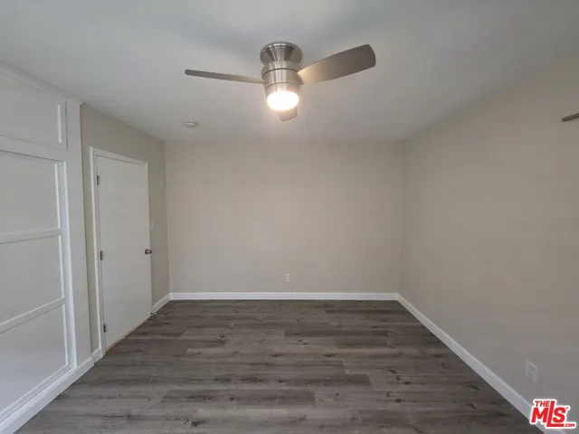 a view of a room with wooden floor and a ceiling fan