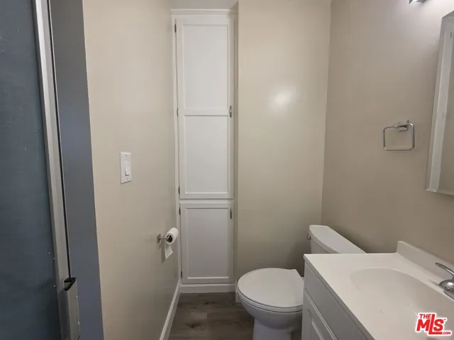 a bathroom with a granite countertop toilet a sink and a large mirror