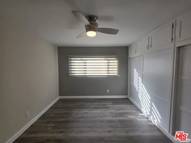 an empty room with wooden floor fan and windows