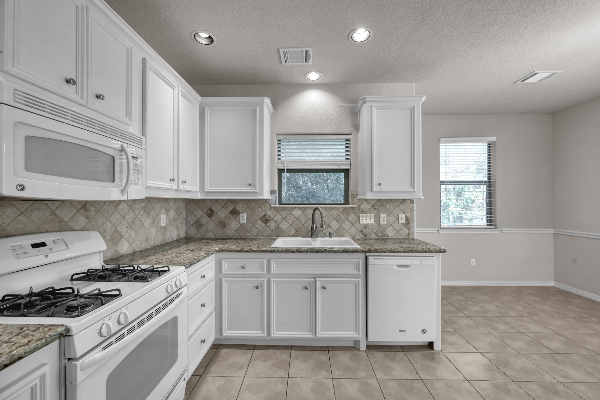 130 April Cove Conroe, TX 77356 - Photo 16 of 36 a kitchen with granite countertop white cabinets and white appliances