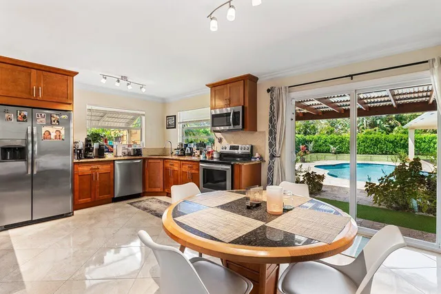 a dining room with stainless steel appliances furniture a large window and a kitchen view