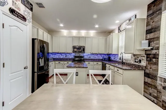 a kitchen with stainless steel appliances kitchen island granite countertop a refrigerator and a stove top oven