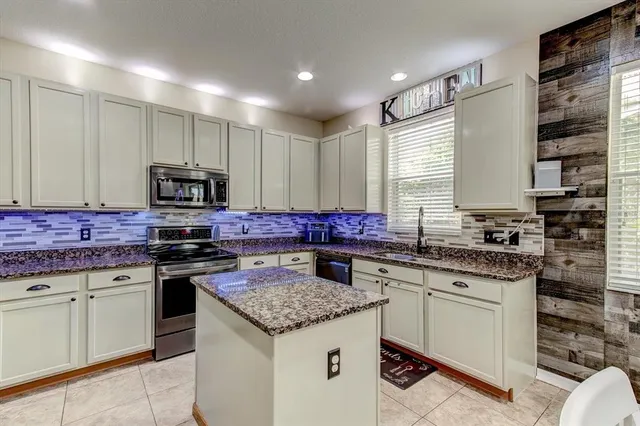 a kitchen with granite countertop stainless steel appliances a sink stove top oven and cabinets