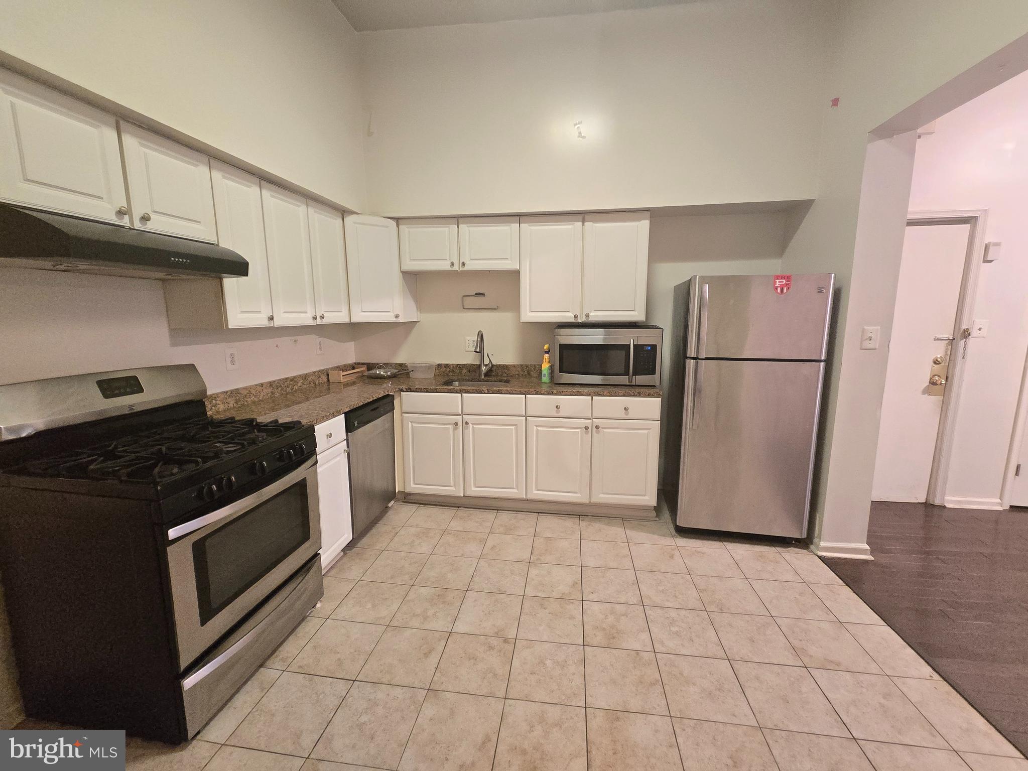 1304 Walnut Street, Unit 2 Philadelphia, PA 19107 - Photo 14 of 33 a kitchen with a stove a sink dishwasher a refrigerator and cabinets