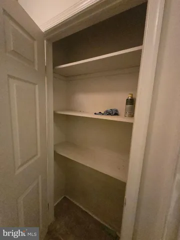 a view of an empty room with wooden floor and fan