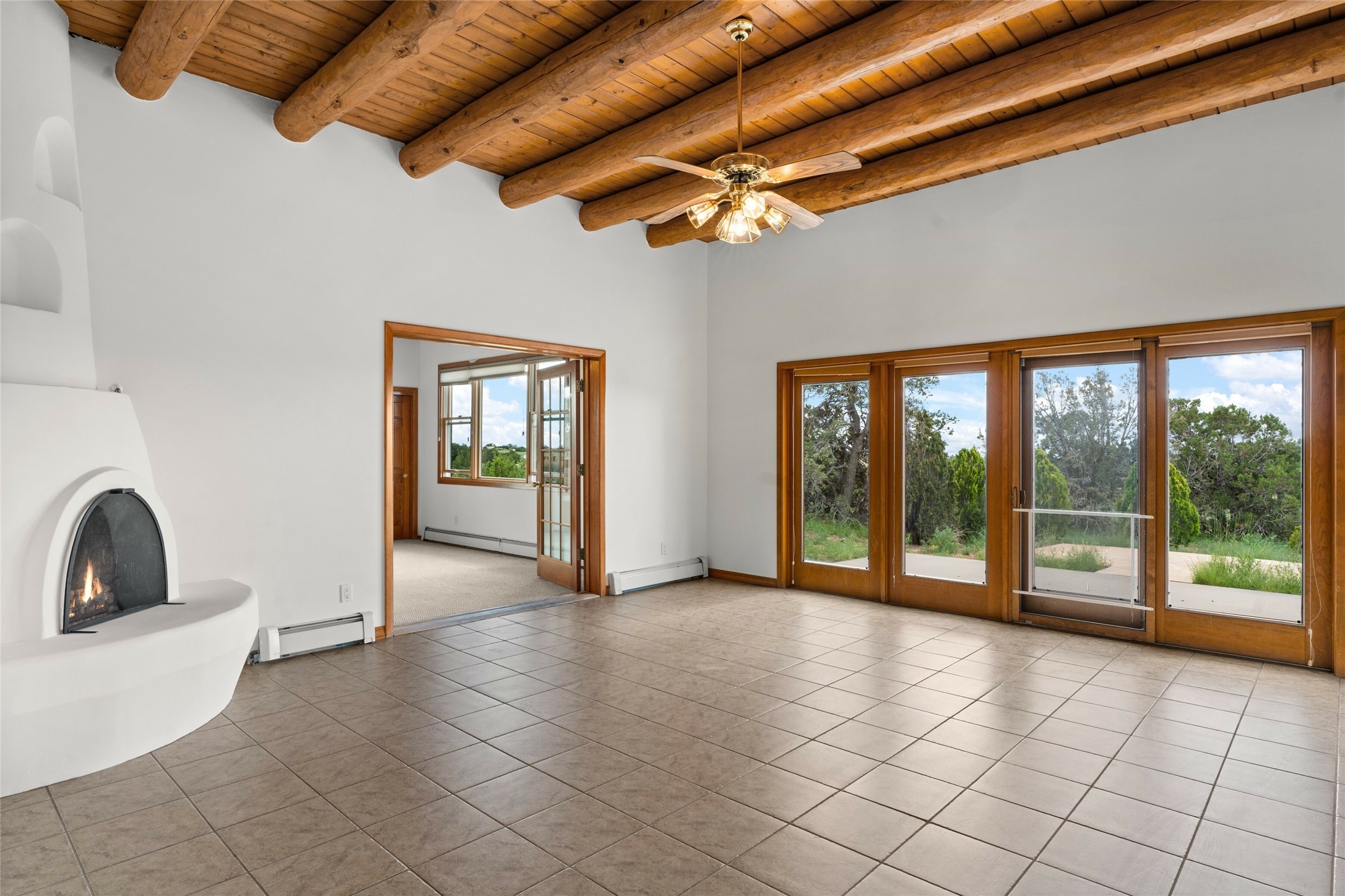 34 Moya Loop Santa Fe, NM 87508 - Photo 1 of 1 Living room with kiva fireplace, vigas and tile floors