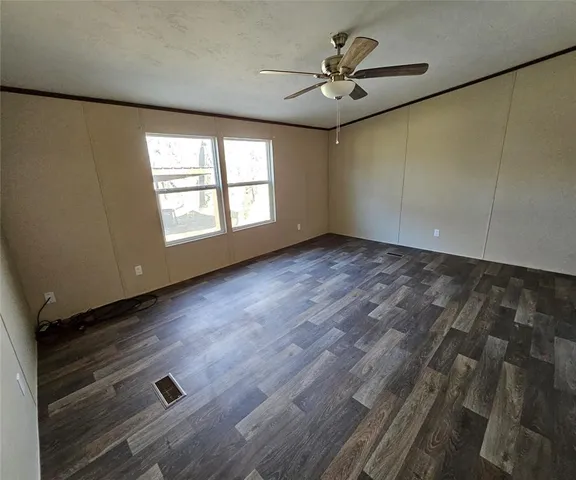 an empty room with wooden floor fan and windows