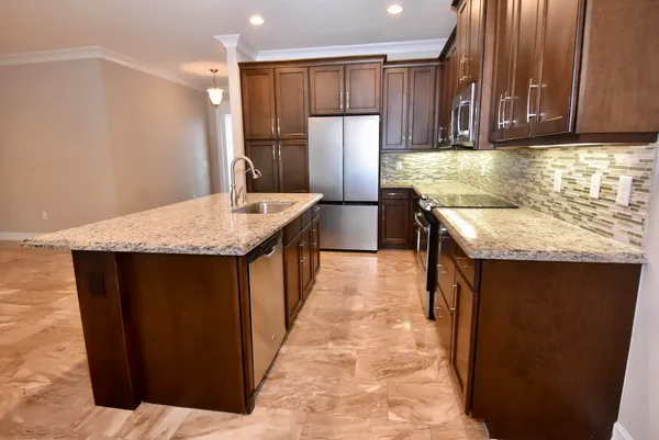 a kitchen with stainless steel appliances granite countertop wooden cabinets a refrigerator and a sink