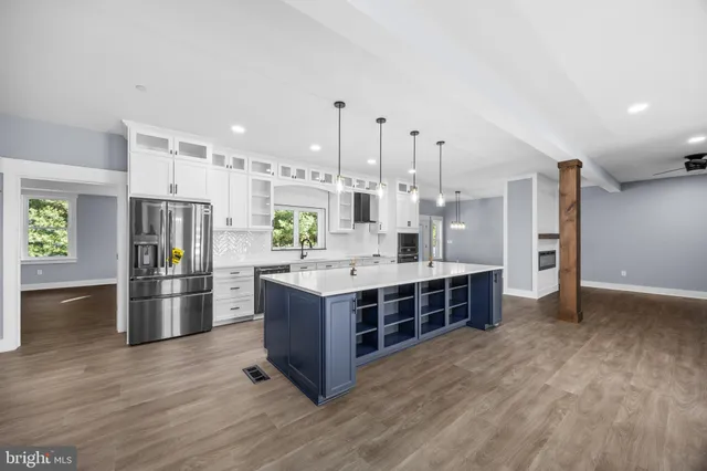 a large kitchen with kitchen island a stove a sink a center island and wooden floor