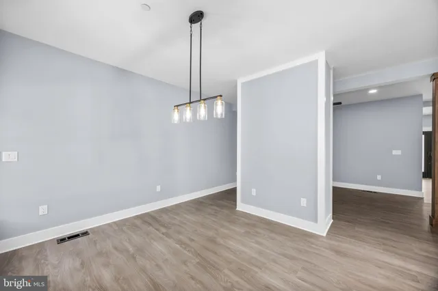 an empty room with wooden floor ceiling fan and windows
