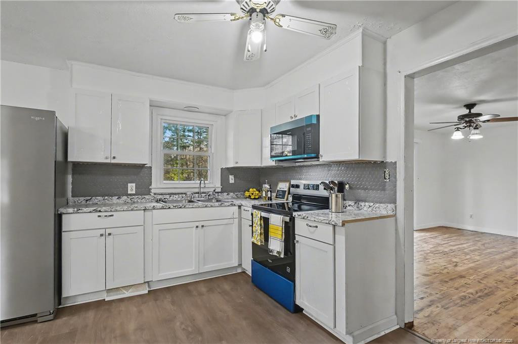 347 Forest Road Lumberton, NC 28358 - Photo 26 of 45 a kitchen with stainless steel appliances granite countertop a stove top oven a sink dishwasher and a refrigerator with wooden floor