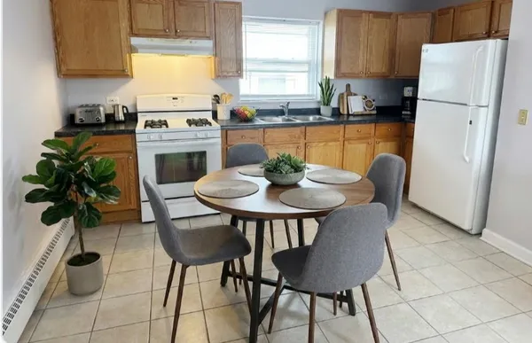 a kitchen with stainless steel appliances a dining table chairs and a refrigerator