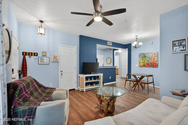 a living room with furniture kitchen view and a wooden floor