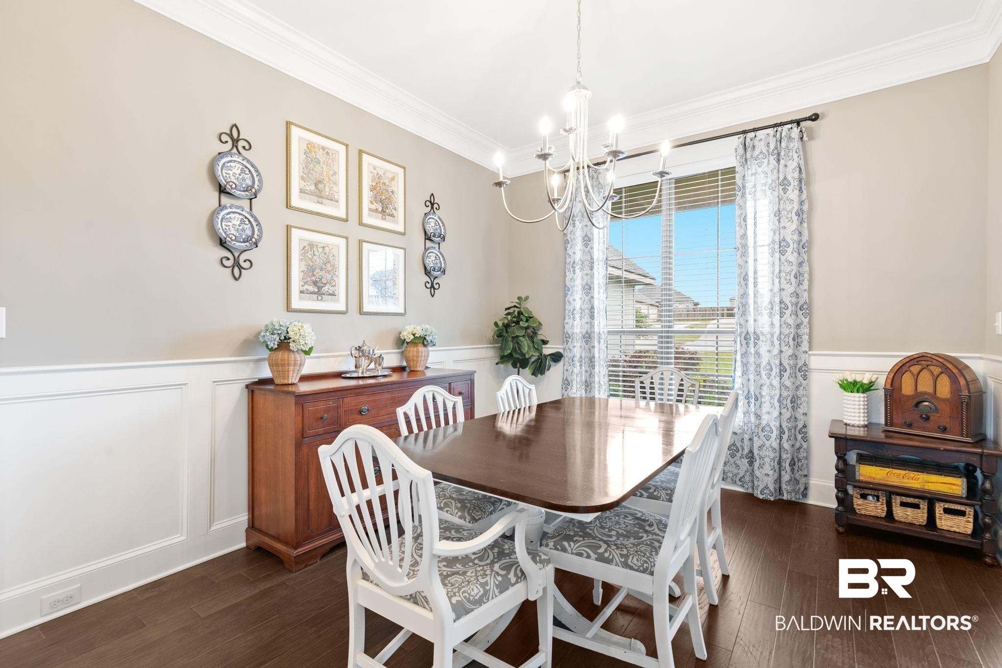 13233 Ibis Boulevard Daphne, AL 36527 - Photo 10 of 100 Dining area featuring a prominent window, crown molding, chair rail with wainscoting, a chandelier, and wood-finish flooring