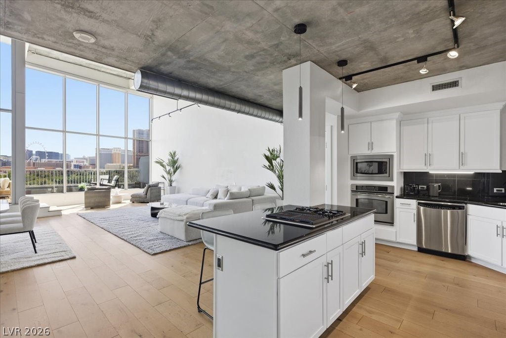 360 East Desert Inn Road, Unit 604 Las Vegas, NV 89109 - Photo 18 of 28 An open concept living area boasts a modern kitchen island with integrated cooktop and city views from expansive windows.