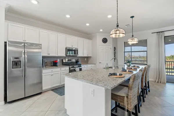 a kitchen with stainless steel appliances granite countertop a dining table chairs and white cabinets