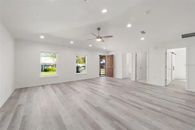 an empty room with windows and ceiling fan