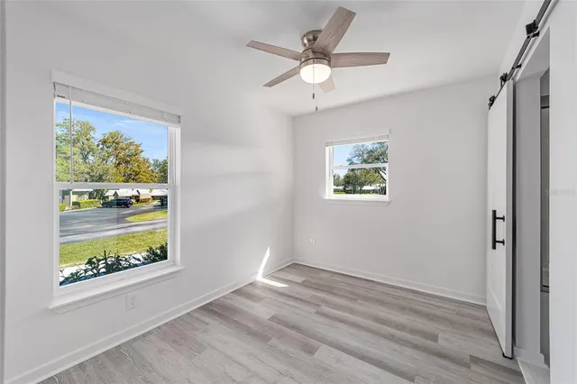 an empty room with wooden floor ceiling fan with window