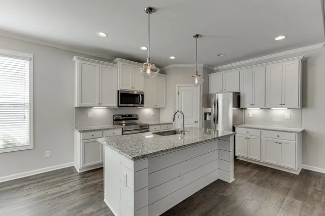 a kitchen with granite countertop a sink stainless steel appliances and white cabinets