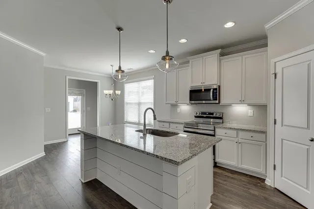 a kitchen with kitchen island granite countertop stainless steel appliances a sink a stove a microwave and wooden floor