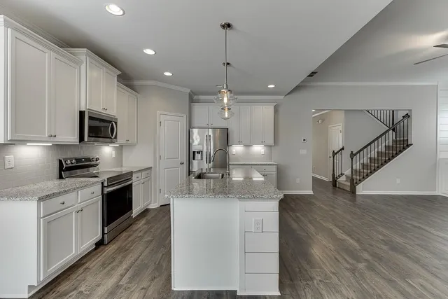 a kitchen with kitchen island a sink stainless steel appliances and wooden floor