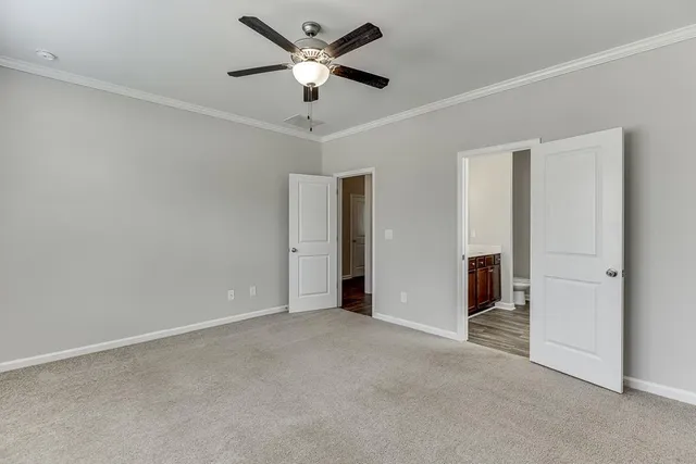 an empty room with chandelier fan and windows