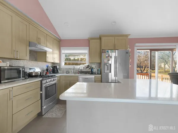 a kitchen with stainless steel appliances granite countertop a refrigerator a sink dishwasher a stove and white countertops with wooden floor