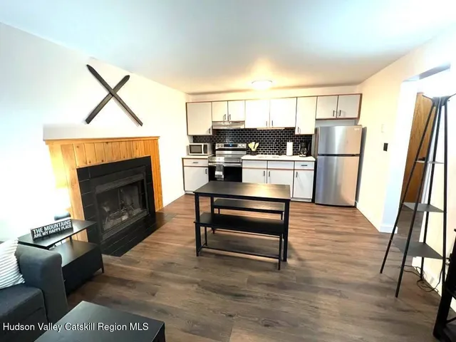 a living room with stainless steel appliances furniture a fireplace and wooden floor
