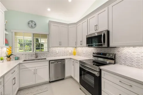 a kitchen with cabinets appliances a sink and a window