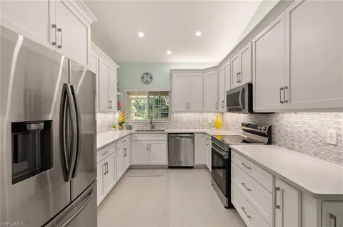 a kitchen with white cabinets stainless steel appliances and a refrigerator